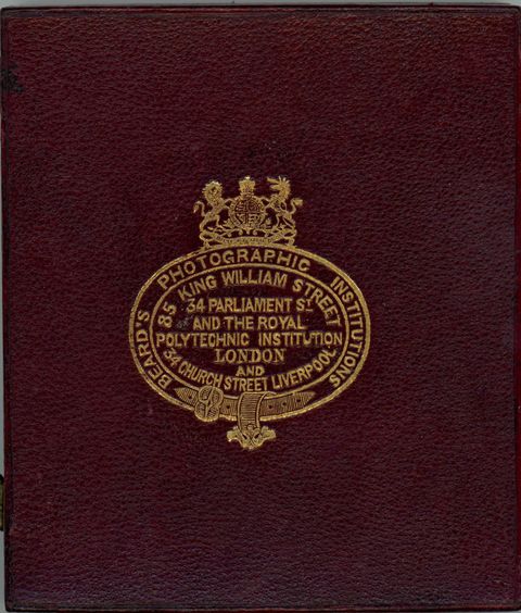 Case. Burgundy-red leather case is stamped with a gold insignia. Text around the border reads, “Beard’s Photographic Institutions”. Text within the insignia reads, “85 King William Street 34 Parliament St and the Royal Polytechnic Institution London and 34 Church Street Liverpool”.