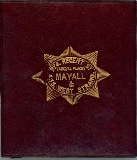 Burgundy-red leather case stamped with a gold insignia. Text within a starburst reads, “224. Regent St (Argyll Place) Mayall & 433. West Strand.”